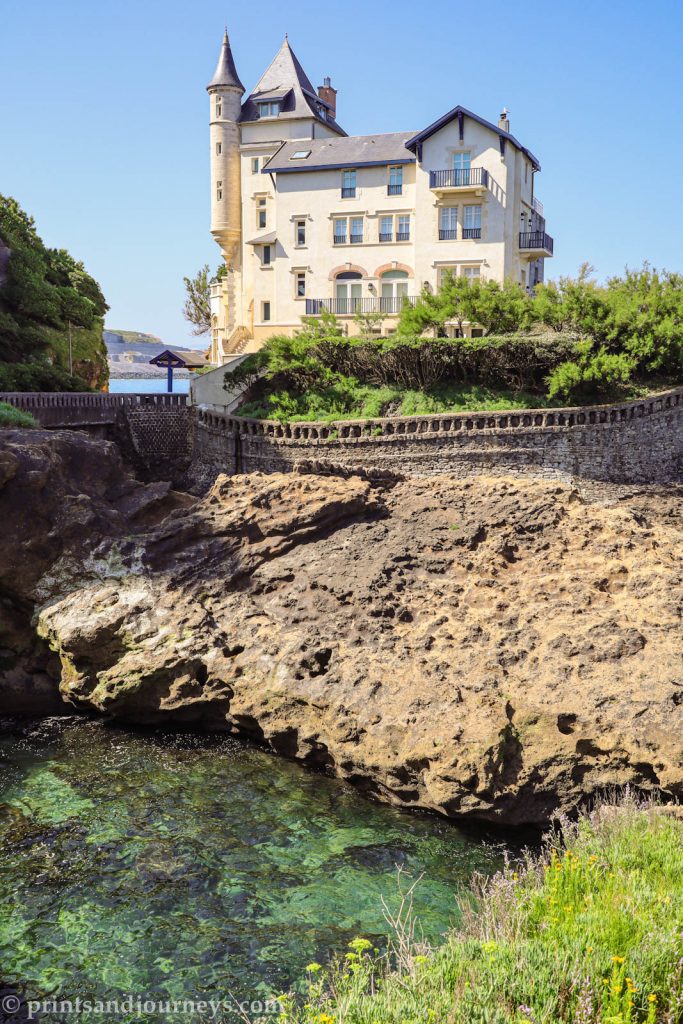 Historic Villa Belza in Biarritz with the sea and rocky shoreline in the foreground.