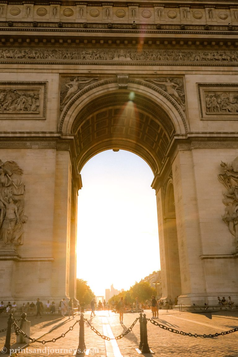 the arc de triumphe head on, with sunset glow coming through the archway