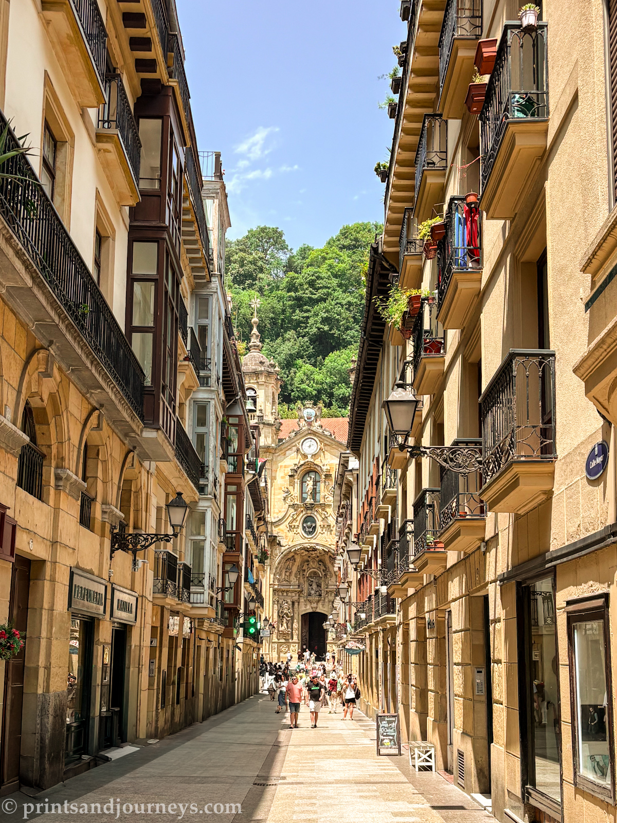 a photo looking down the street of san sebastian's old town with the church at the end